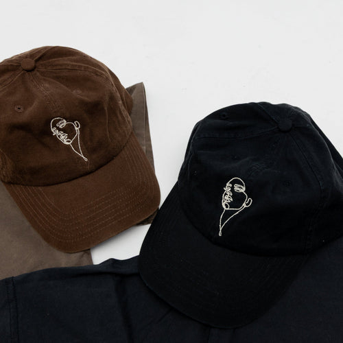 Brown and black baseball caps with embroidered designs on a light gray background